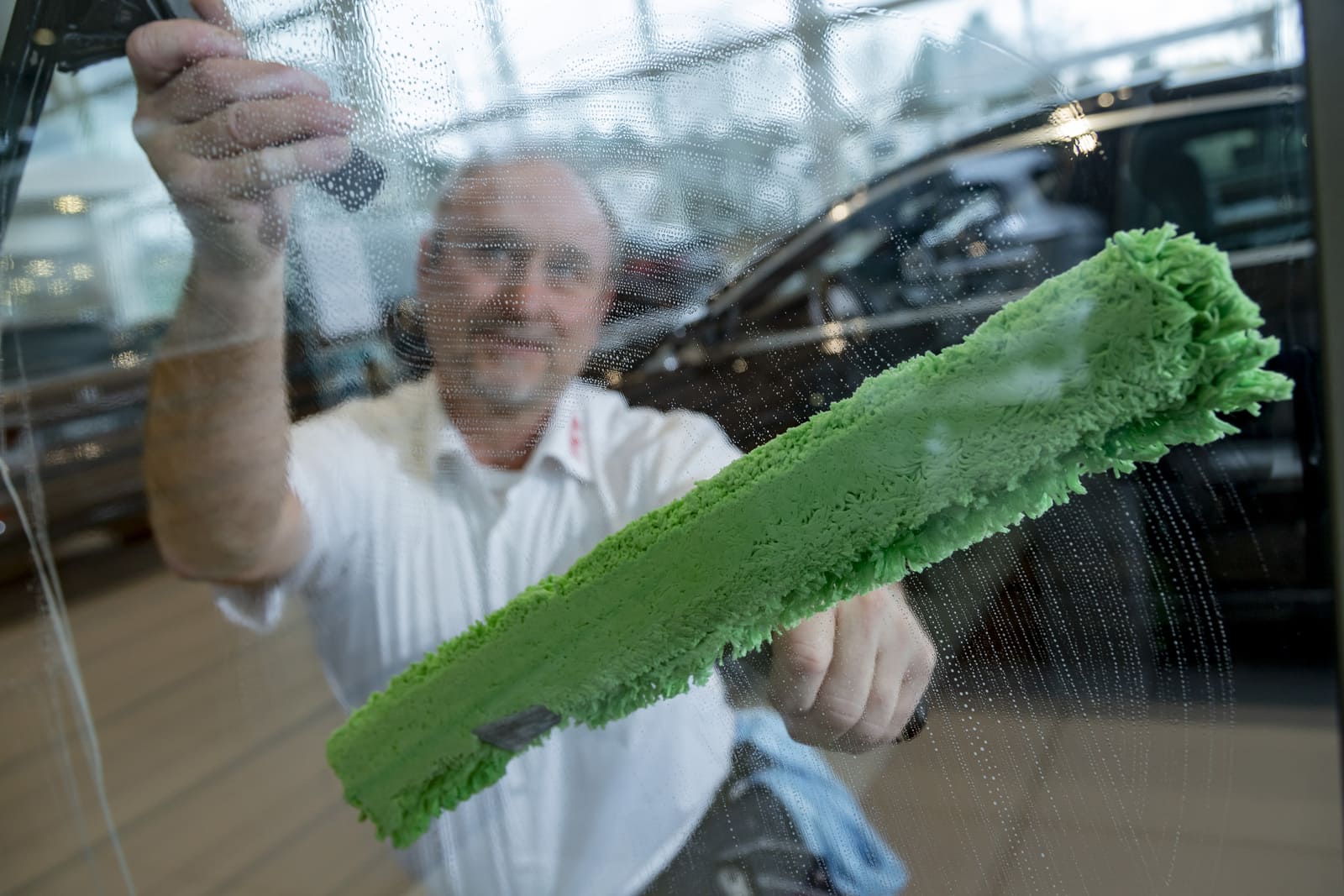 TKW Gebäudereinigung - Glasreinigung und Fensterreinigung - Facharbeiter reinigt Glas mit Wischer und Abzieher