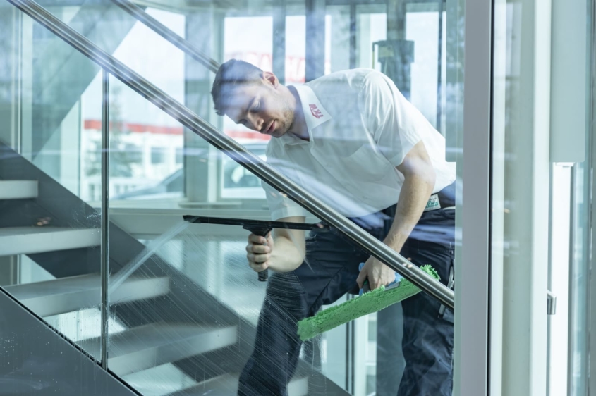 TKW Gebäudereinigung - Glasreinigung - Facharbeiter reinigt Glas im Treppenhaus