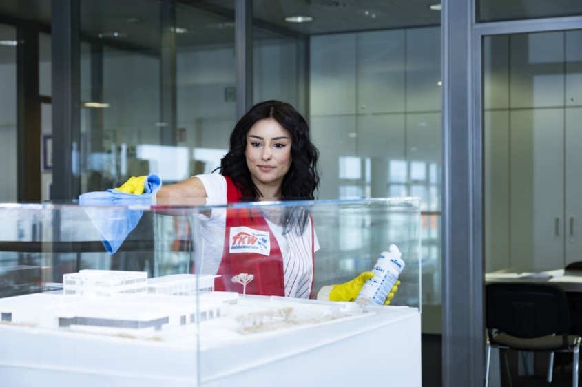 TKW Gebäudereinigung - Unterhaltsreinigung - Reinigung Showrooms - Reinigungskraft reinigt Vitrine aus Glas